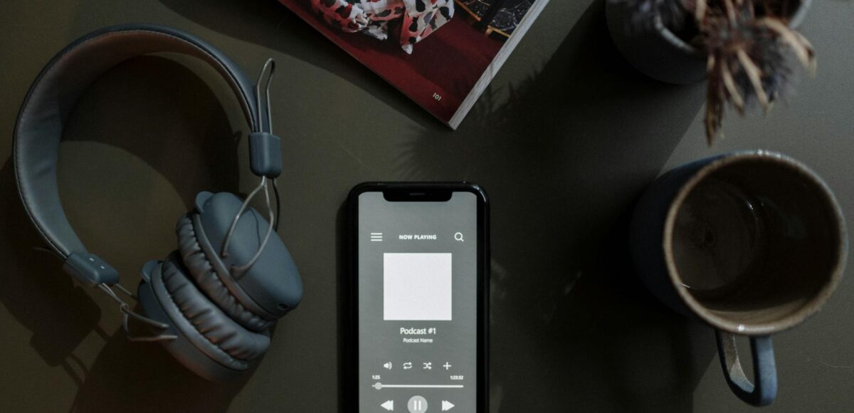 overhead shot of a cellphone between a mug and headphones